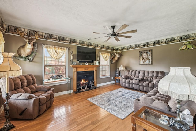 living room with baseboards, wood finished floors, ceiling fan, and a textured ceiling