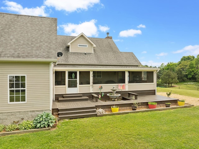 rear view of house with a chimney, a wooden deck, a sunroom, roof with shingles, and a lawn