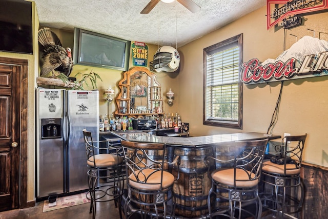 bar with stainless steel fridge, a textured ceiling, a dry bar, and ceiling fan