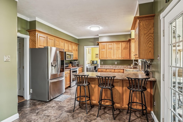 kitchen with crown molding, a sink, a breakfast bar, stainless steel appliances, and a peninsula