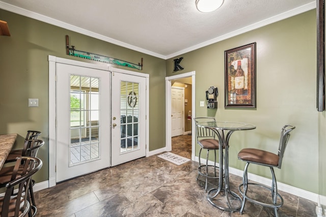 entryway with a textured ceiling, french doors, ornamental molding, and baseboards