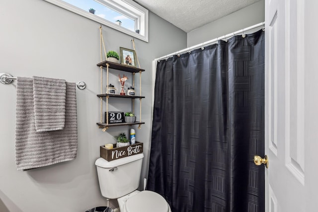 bathroom featuring a textured ceiling, curtained shower, and toilet