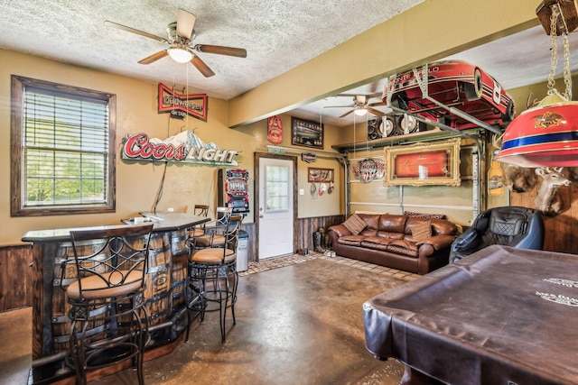 rec room with a ceiling fan, finished concrete flooring, and a textured ceiling