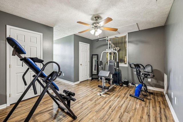 exercise area with a textured ceiling, ceiling fan, wood finished floors, and baseboards