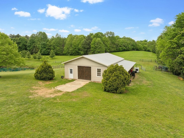 view of pole building with a lawn, fence, and driveway