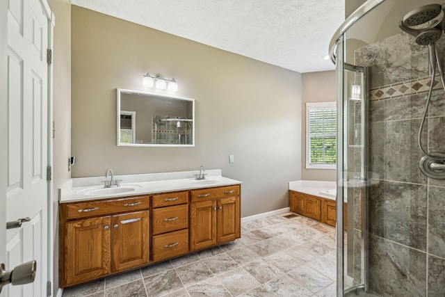 bathroom featuring double vanity, a textured ceiling, a shower stall, and a sink