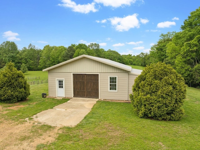 detached garage featuring fence and concrete driveway