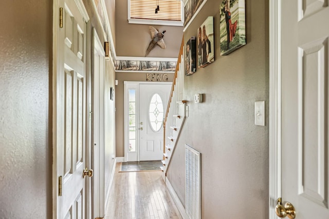 entrance foyer with stairway, visible vents, hardwood / wood-style floors, and a textured wall