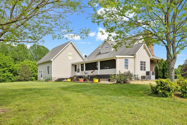 rear view of property featuring a chimney, a shingled roof, central air condition unit, a lawn, and a sunroom