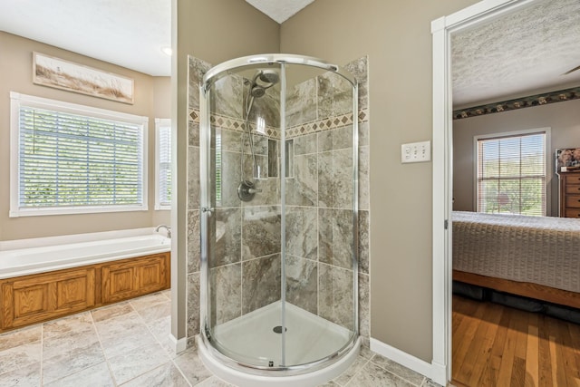 ensuite bathroom featuring a garden tub, a shower stall, and plenty of natural light