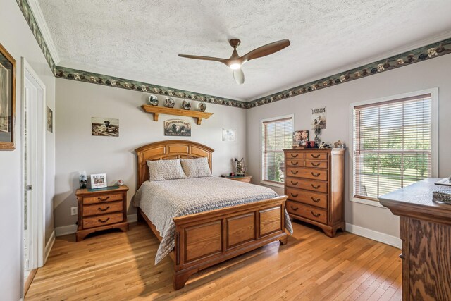 bedroom featuring a textured ceiling, multiple windows, and light wood-type flooring