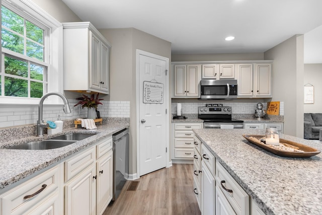 1356 Sayles Cir, Lawrenceburg, TN 38464 - kitchen with light wood finished floors, a sink, decorative backsplash, light stone counters, and appliances with stainless steel finishes