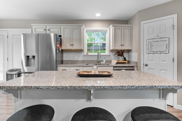 1356 Sayles Cir, Lawrenceburg, TN 38464 - kitchen featuring a sink, decorative backsplash, a breakfast bar area, light wood-style flooring, and stainless steel fridge with ice dispenser