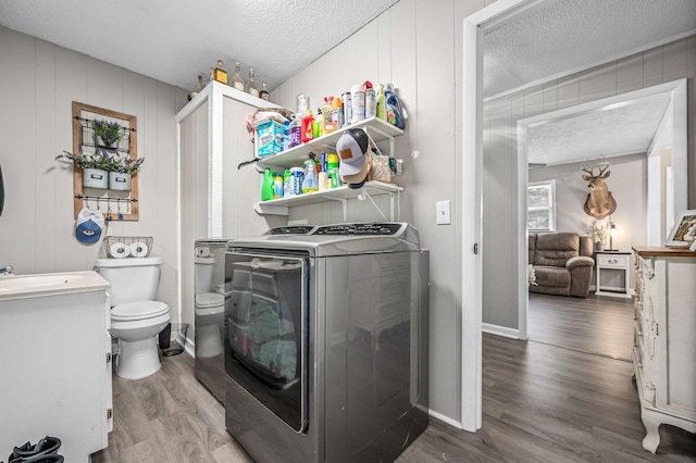 laundry room featuring a textured ceiling, wood finished floors, and washing machine and clothes dryer