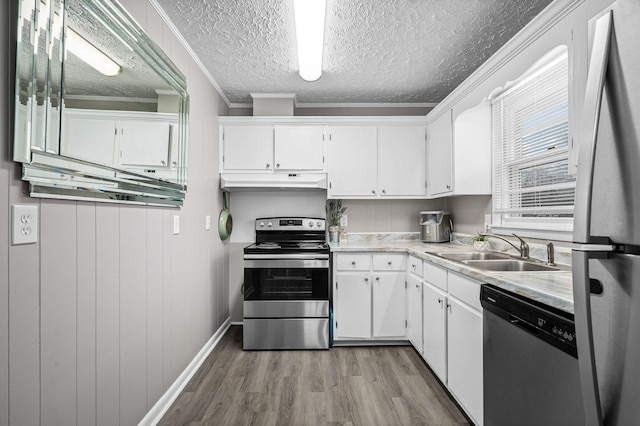 kitchen with white cabinetry, a sink, appliances with stainless steel finishes, under cabinet range hood, and light wood-type flooring