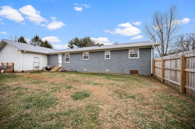 back of house featuring metal roof, crawl space, a yard, and fence