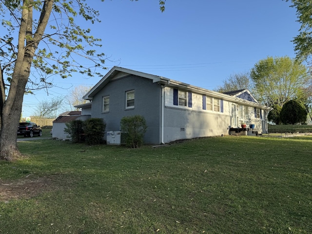 view of side of property with a yard, crawl space, and brick siding