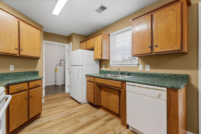 kitchen featuring a sink, visible vents, water heater, light wood-style flooring, and white appliances