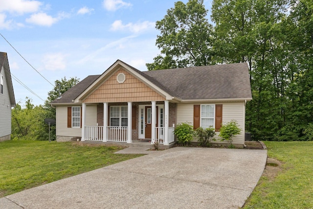 view of front of home with roof with shingles, covered porch, and a front yard