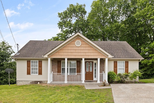 view of front of home with a front lawn, a shingled roof, and covered porch