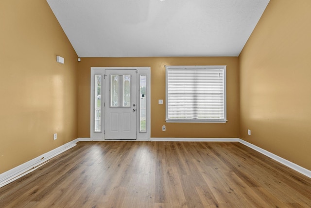 foyer entrance featuring lofted ceiling, wood finished floors, and baseboards