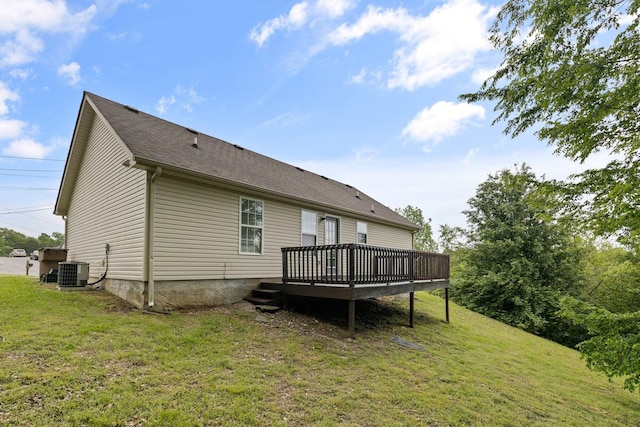 rear view of property featuring a deck, a yard, central AC, and roof with shingles