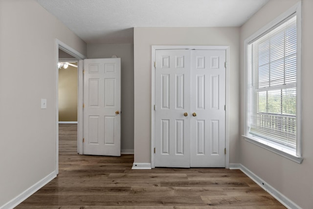 unfurnished bedroom with wood finished floors, baseboards, and a closet