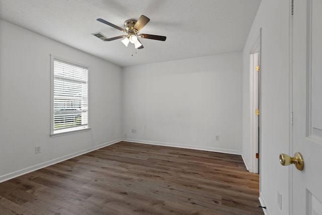 unfurnished room with visible vents, ceiling fan, dark wood finished floors, and baseboards
