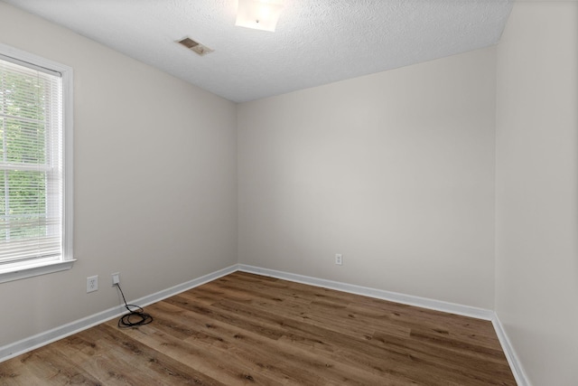 spare room with baseboards, visible vents, wood finished floors, and plenty of natural light