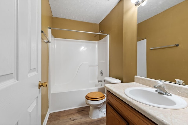 bathroom with a textured ceiling, toilet, shower / bathing tub combination, wood finished floors, and vanity