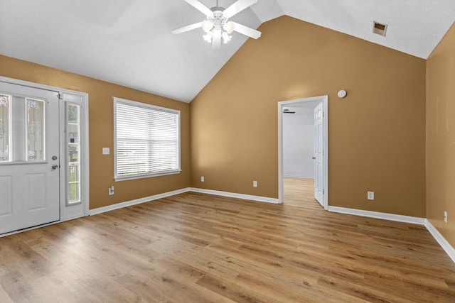foyer entrance with ceiling fan, light wood finished floors, baseboards, visible vents, and high vaulted ceiling