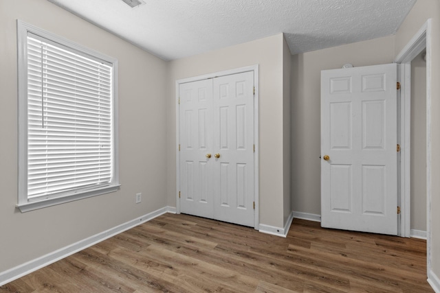 unfurnished bedroom with a closet, wood finished floors, and baseboards