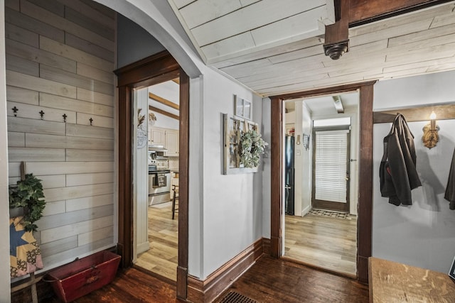 hallway featuring baseboards, arched walkways, and dark wood-style flooring