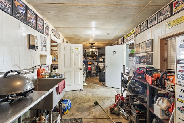 kitchen featuring wooden walls, unfinished concrete flooring, visible vents, and a ceiling fan