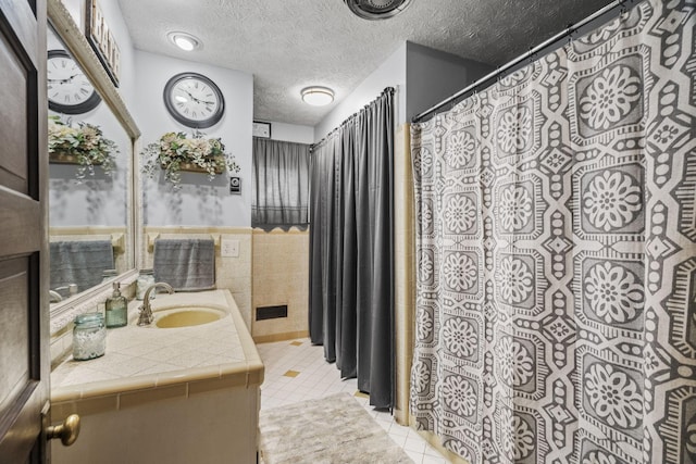 full bathroom with tile walls, vanity, a wainscoted wall, visible vents, and tile patterned flooring