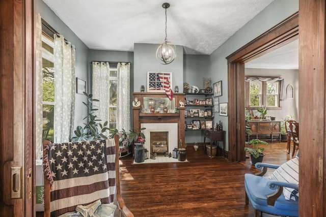 sitting room featuring a notable chandelier, a fireplace with flush hearth, and wood finished floors