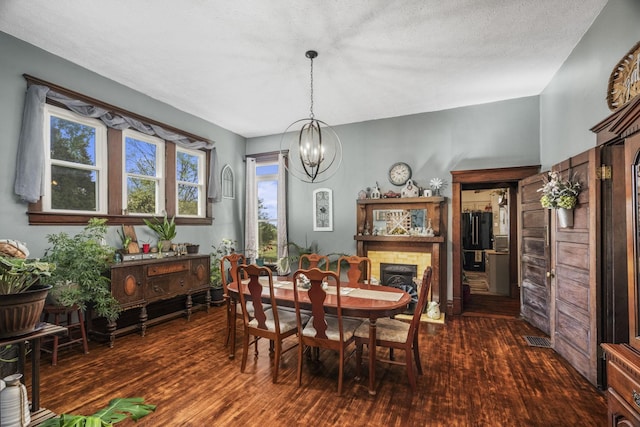 dining room with dark wood finished floors, visible vents, and an inviting chandelier