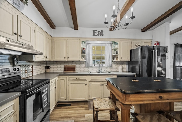 kitchen with a sink, cream cabinets, freestanding refrigerator, and stainless steel electric range