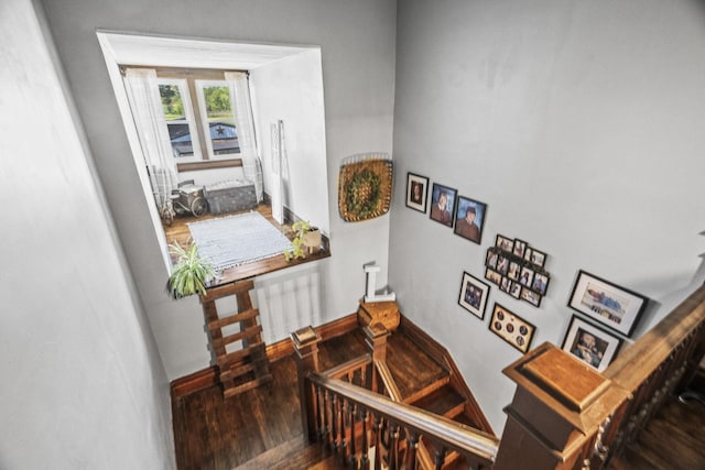 staircase with wood finished floors, baseboards, and radiator