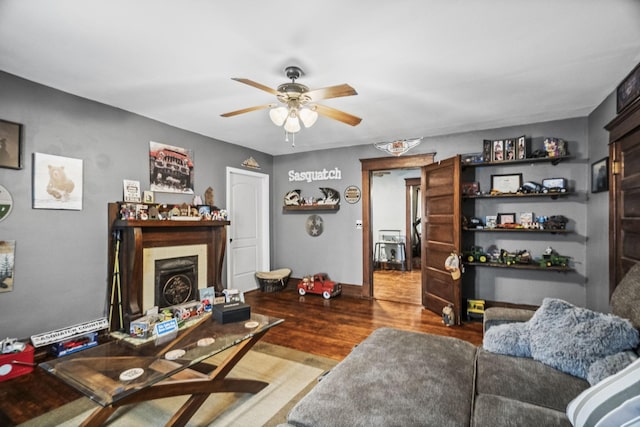 living room with baseboards, wood finished floors, ceiling fan, and a fireplace