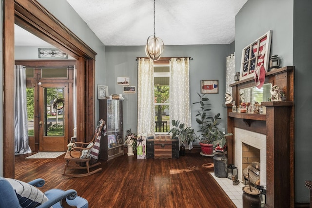 interior space with a textured ceiling, wood finished floors, a tile fireplace, and a chandelier