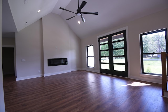 unfurnished living room featuring ceiling fan, dark wood finished floors, high vaulted ceiling, baseboards, and a glass covered fireplace