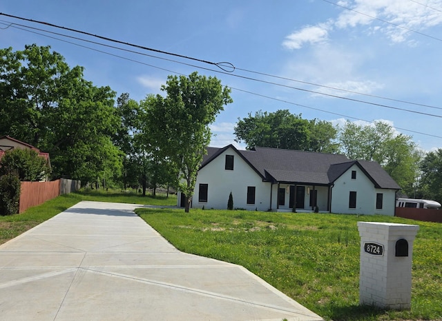 view of front facade featuring fence, stucco siding, driveway, and a front yard