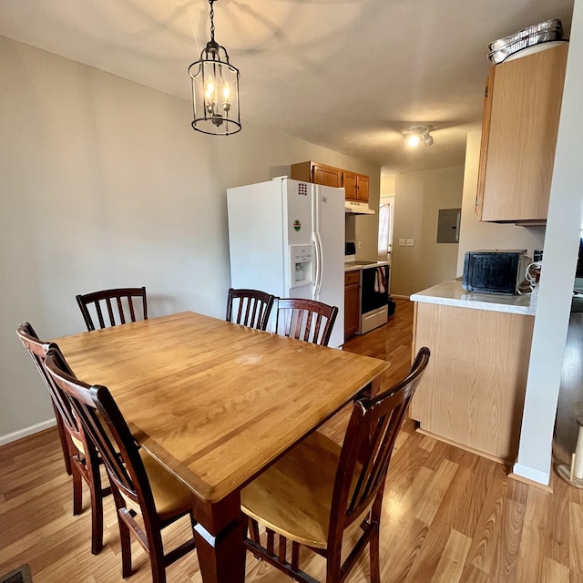 dining area with baseboards, an inviting chandelier, electric panel, and light wood-style flooring