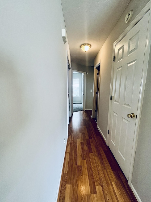 hallway featuring dark wood-style floors and baseboards