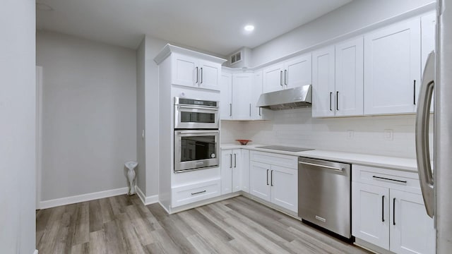 kitchen featuring light wood-style flooring, visible vents, stainless steel appliances, light countertops, and under cabinet range hood