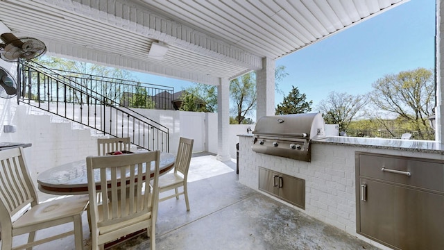 view of patio / terrace featuring fence, area for grilling, outdoor dining area, exterior kitchen, and stairs
