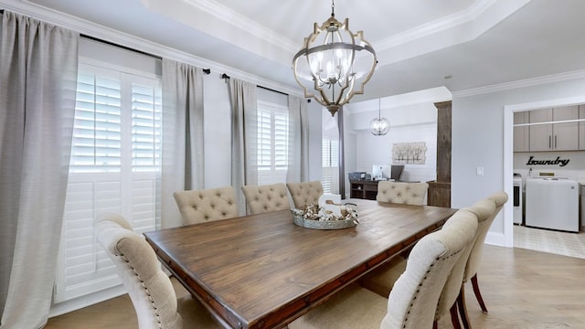 dining space with light wood-style flooring, a chandelier, washing machine and dryer, a raised ceiling, and crown molding