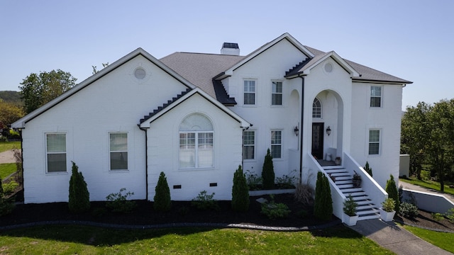 view of front of home with a chimney, stairs, and brick siding