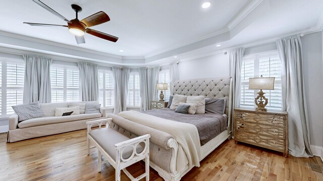 bedroom featuring ornamental molding, a raised ceiling, multiple windows, and hardwood / wood-style floors